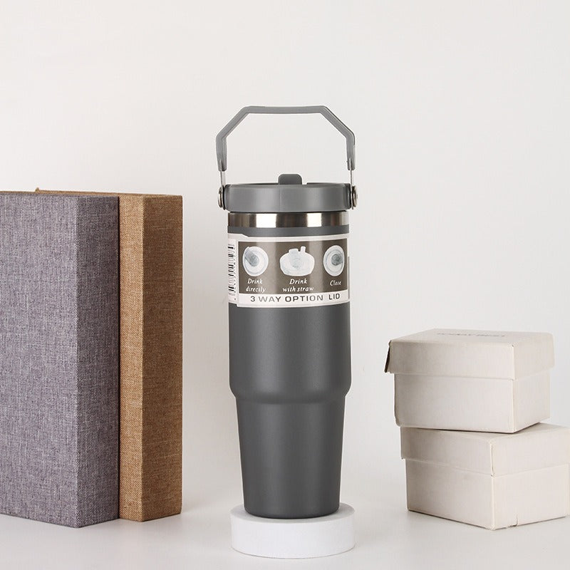 Gray travel tumbler with 3-way lid, next to gift boxes, quality gift item sps street style