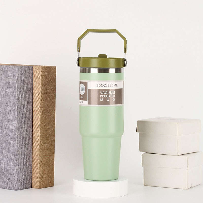 Green vacuum insulated mug with handle, styled with books and gift boxes, quality gift item