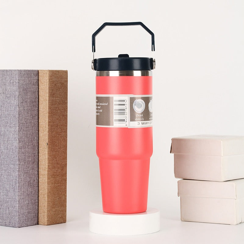 Pink insulated tumbler with black lid and handle, displayed beside boxes and books, sps street style gift